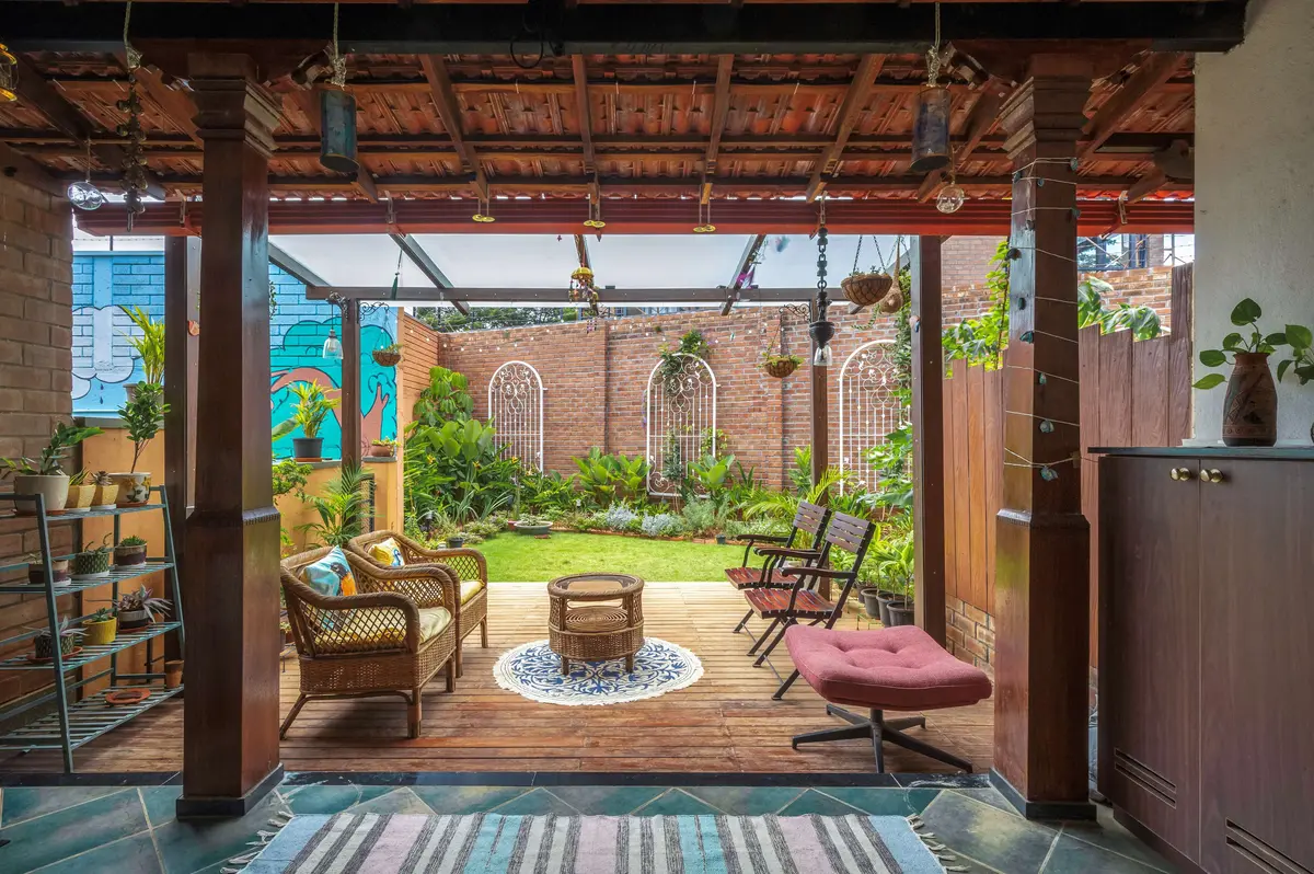 Backyard dining setup with teak table and chairs surrounded by greenery